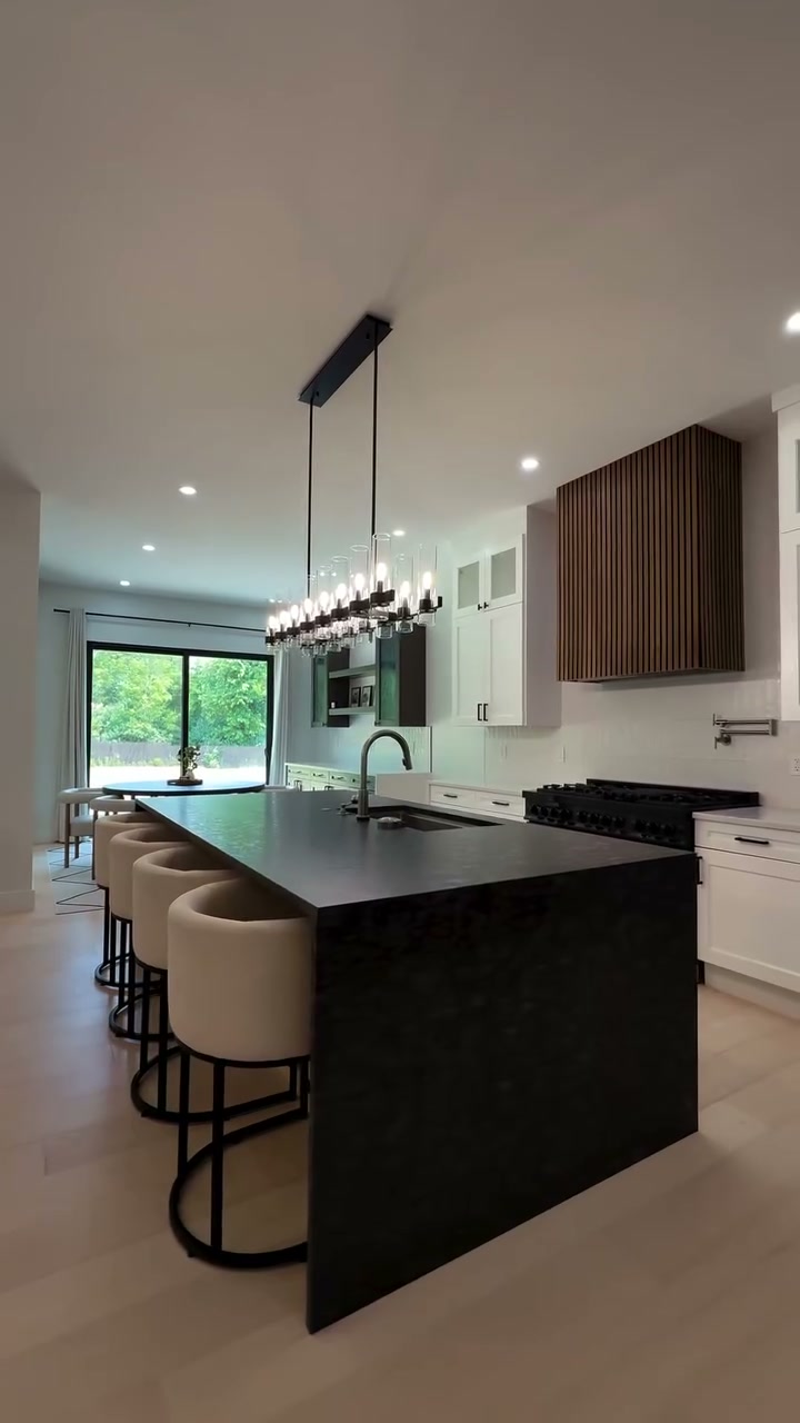 Kitchen with black waterfall island and slat wood hood